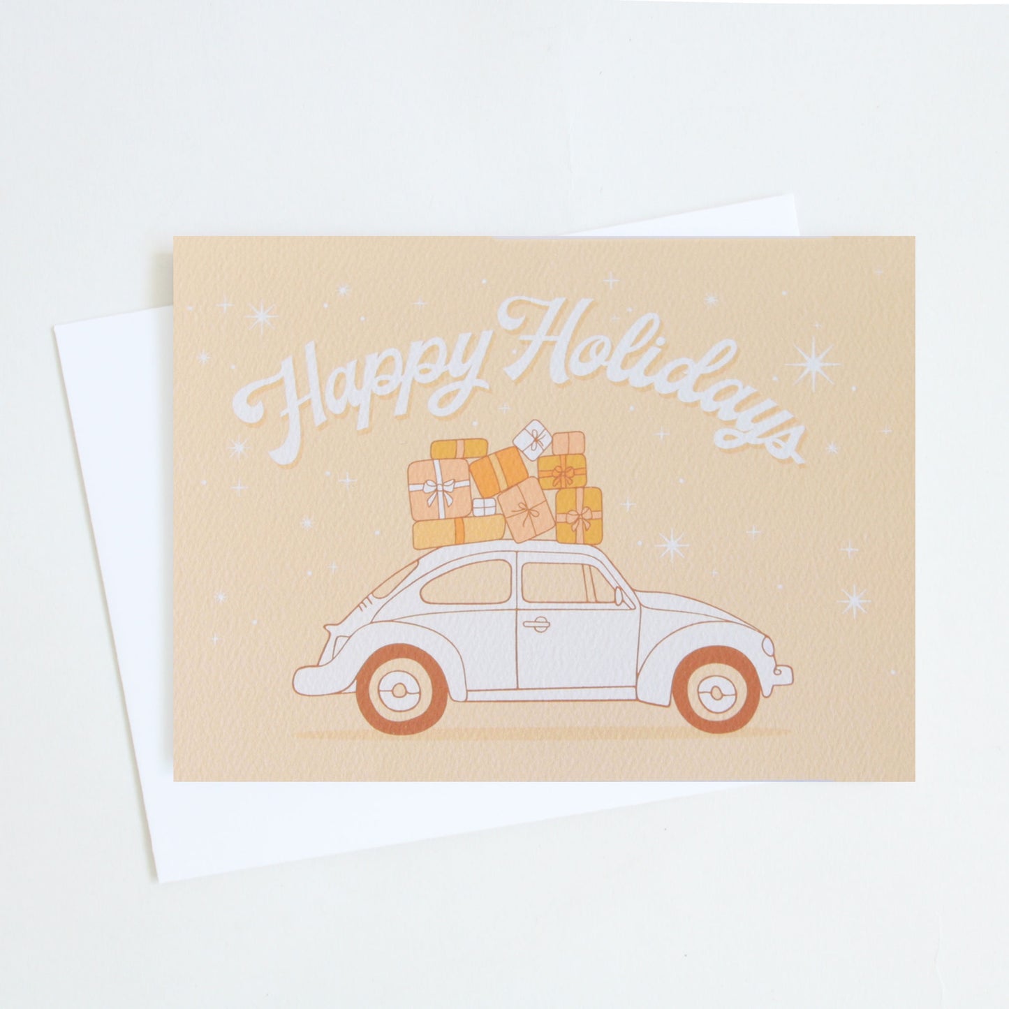 A light orange/yellow card with a graphic of a VW bug with holiday gifts stacked on top along with the words, "Happy Holidays" in a cream colored font.